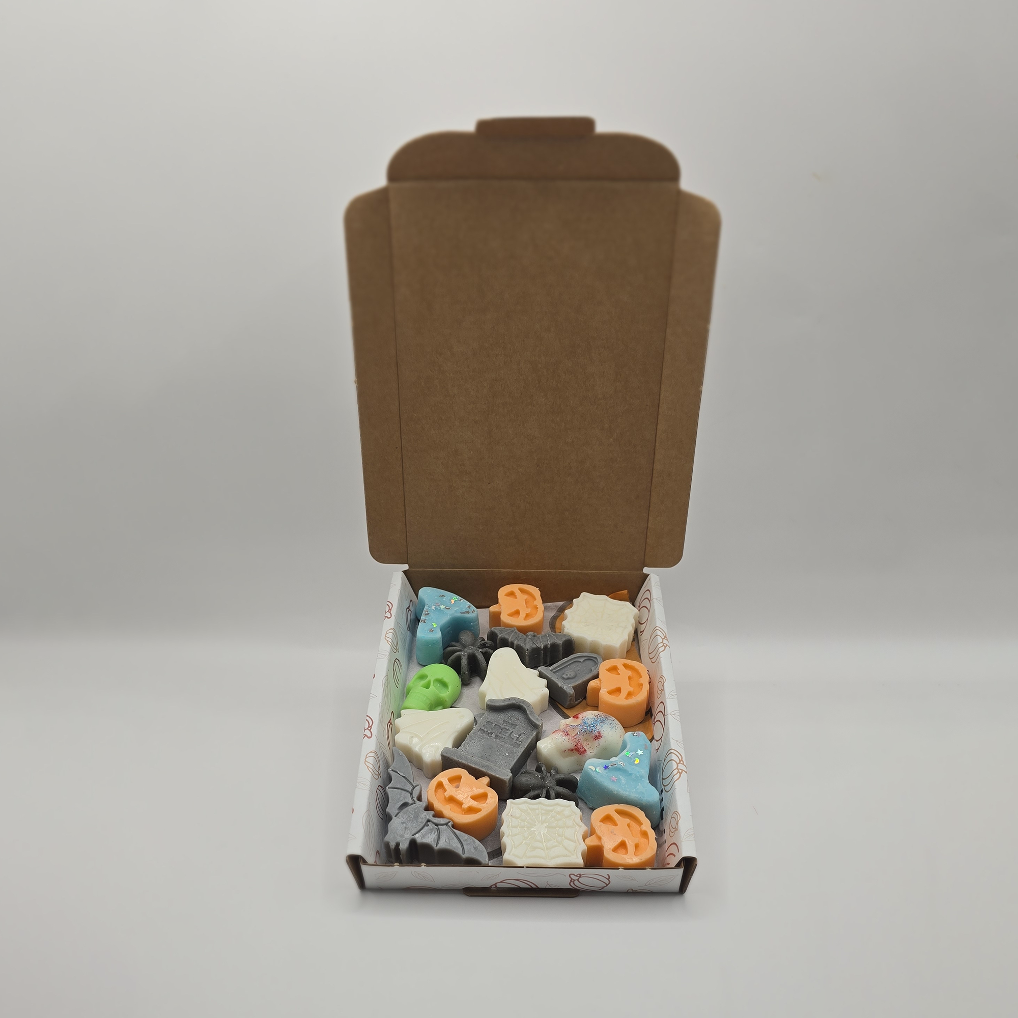 Open cardboard box with assorted colorful stone-like objects on a gray background