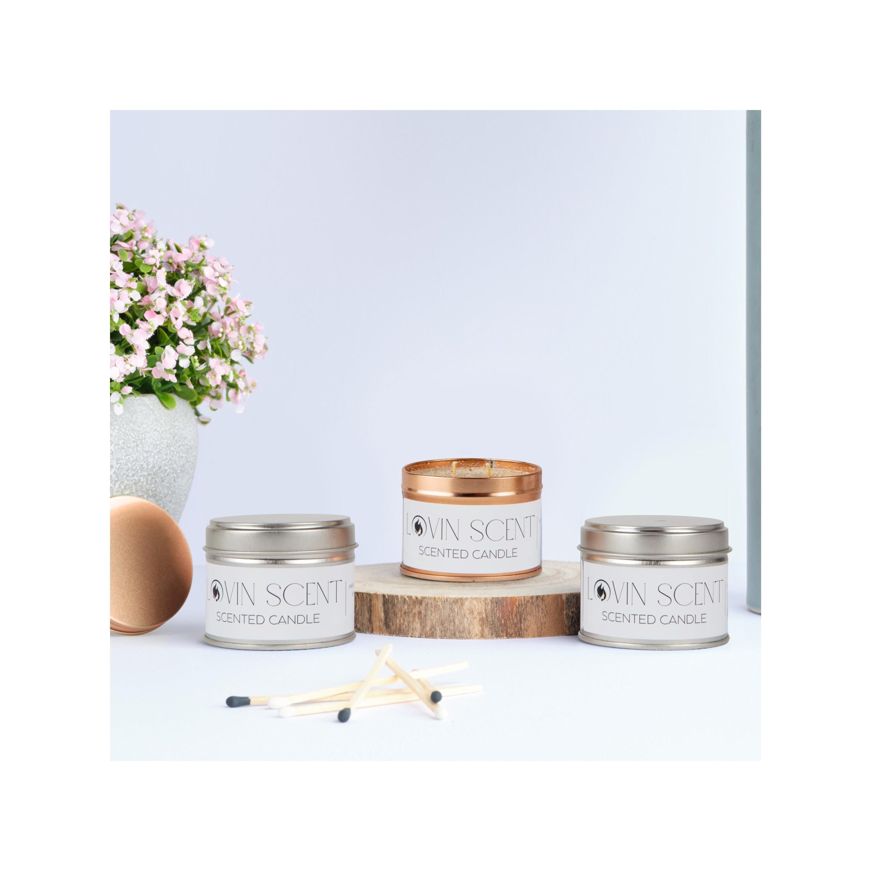 Four scented candles with 'My Scents' branding on a light background, accompanied by a matchbox and a small plant.