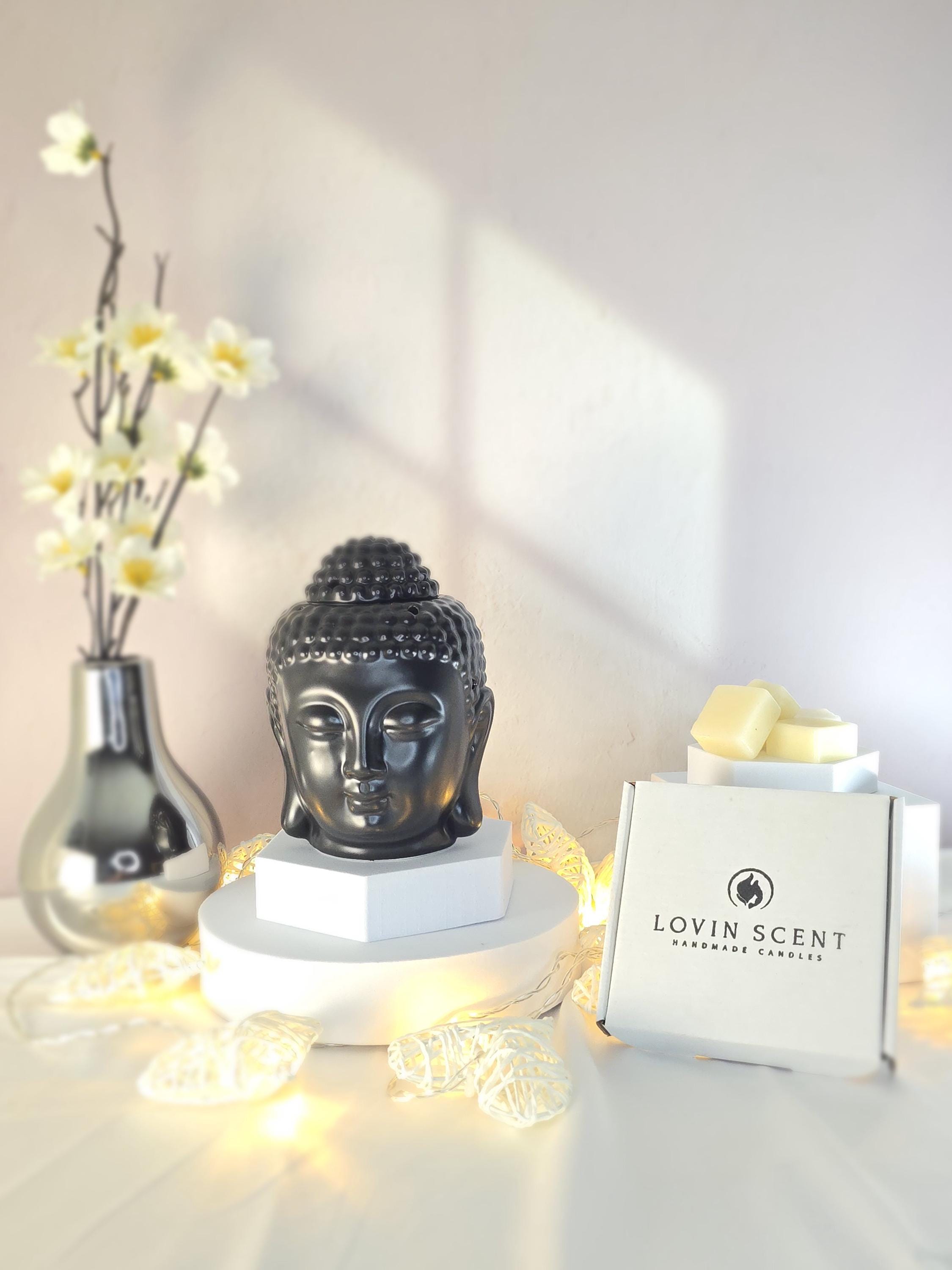 Decorative setup with a Buddha statue, flowers, and a box labeled 'Lovin' Scent' on a light background.