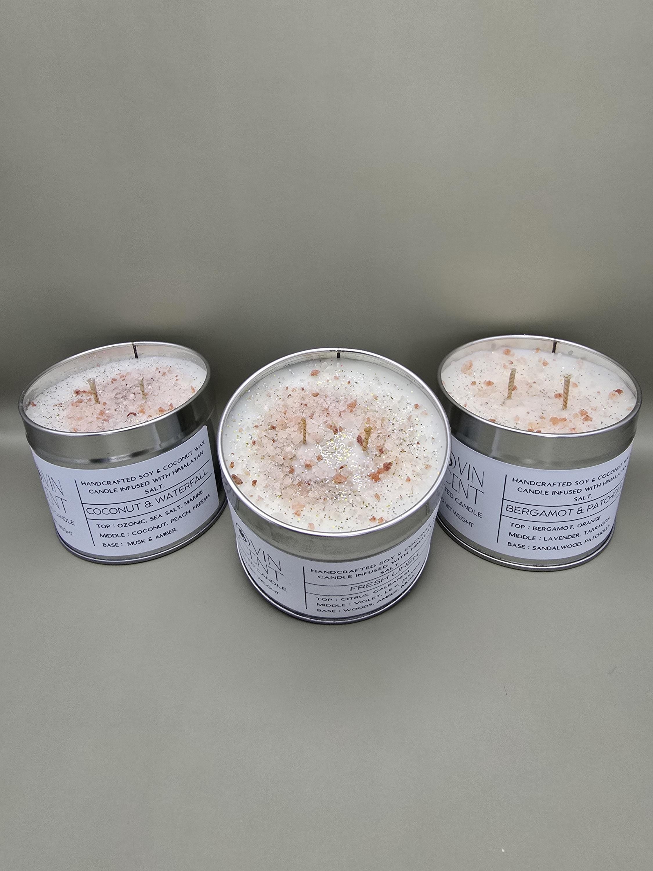 Three tins of bath salts with candles on a gray background