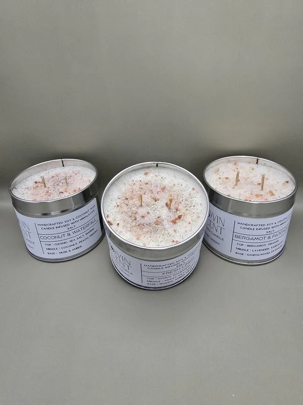 Three tins of bath salts with candles on a gray background