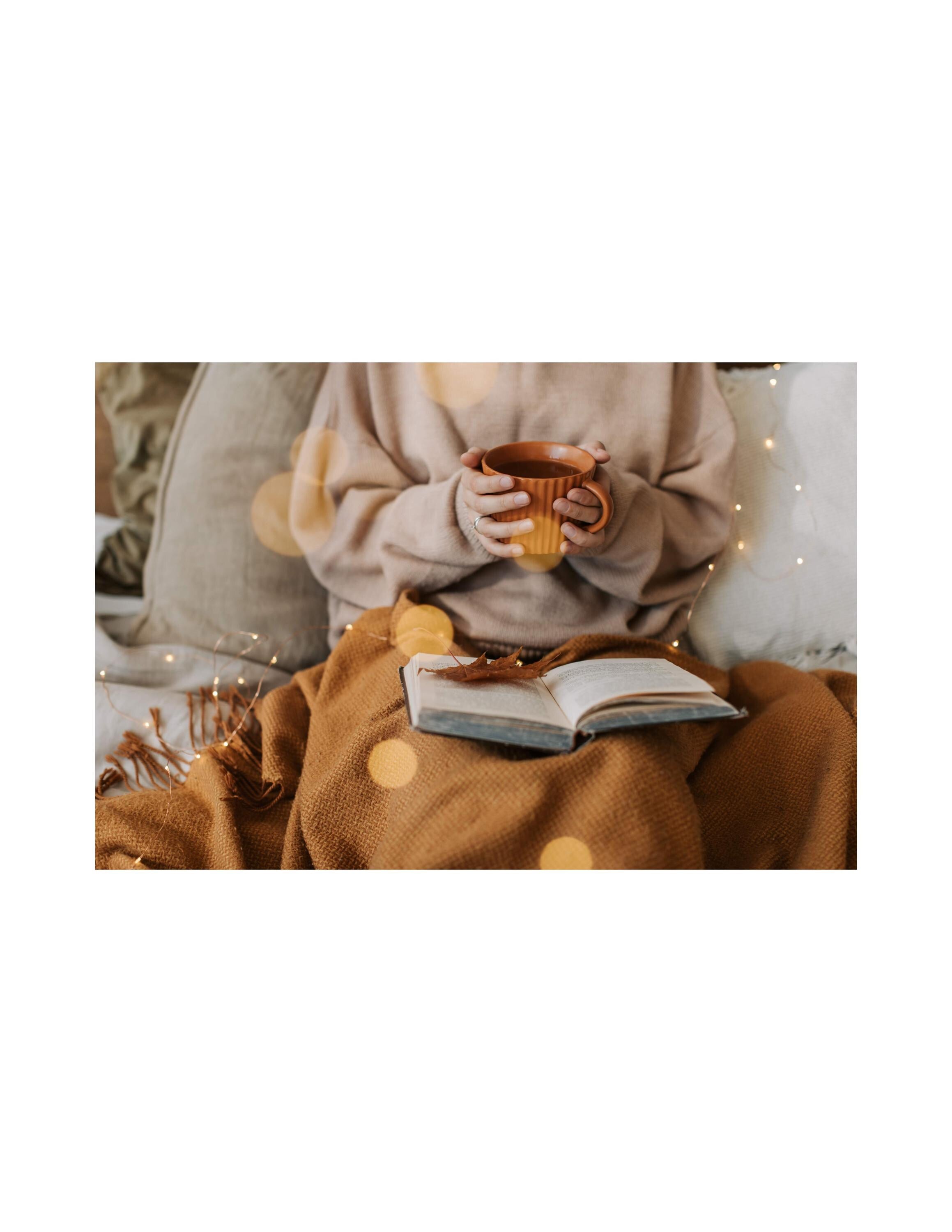 Person sitting cozy with a book and mug, surrounded by warm lighting and textures.
