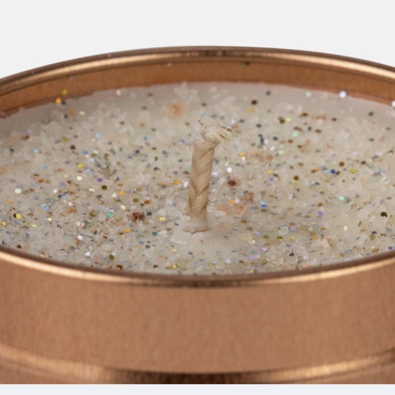 Candle in a tin with decorative glittery texture on a white background