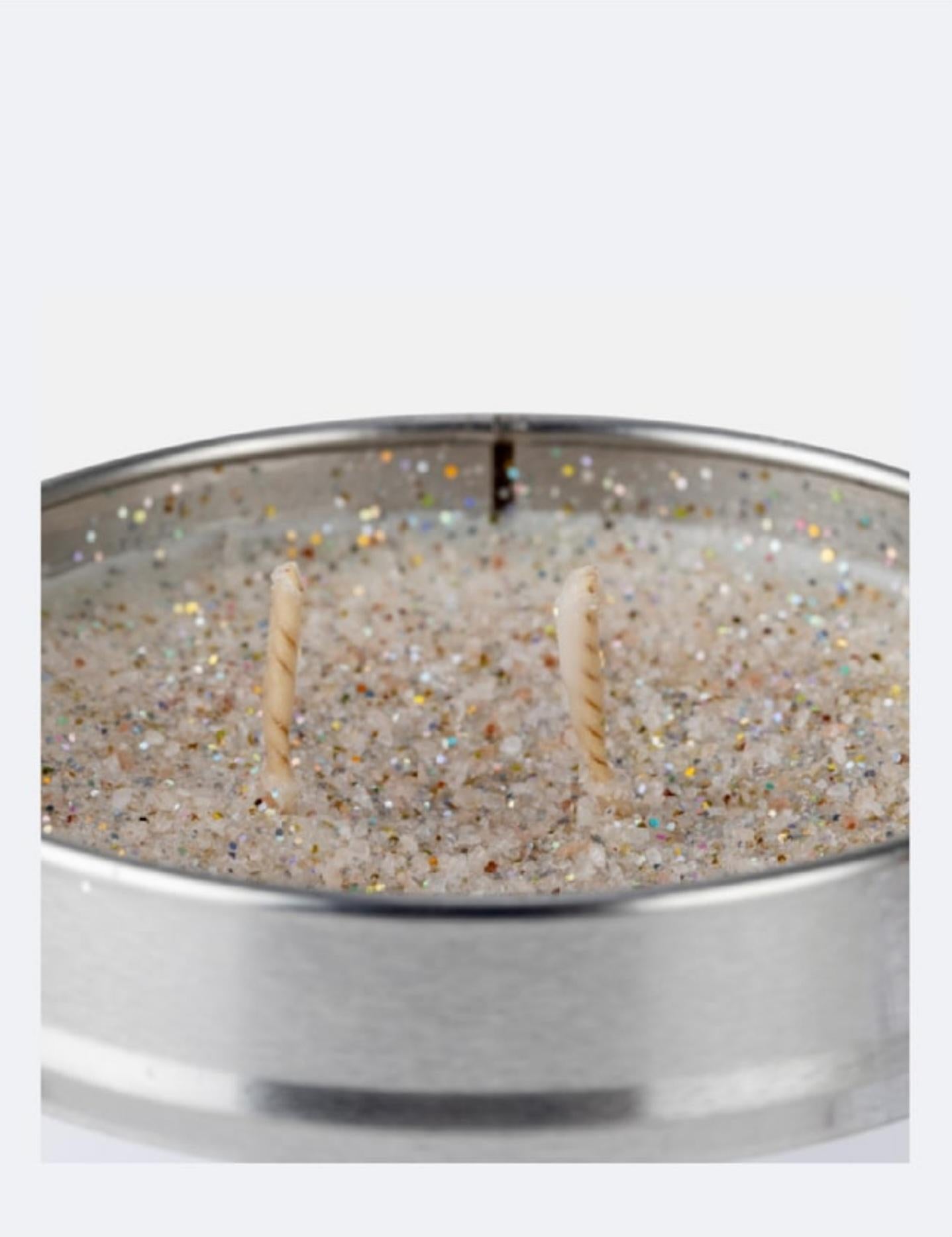 Candle in a metallic container with glittery texture on a white background