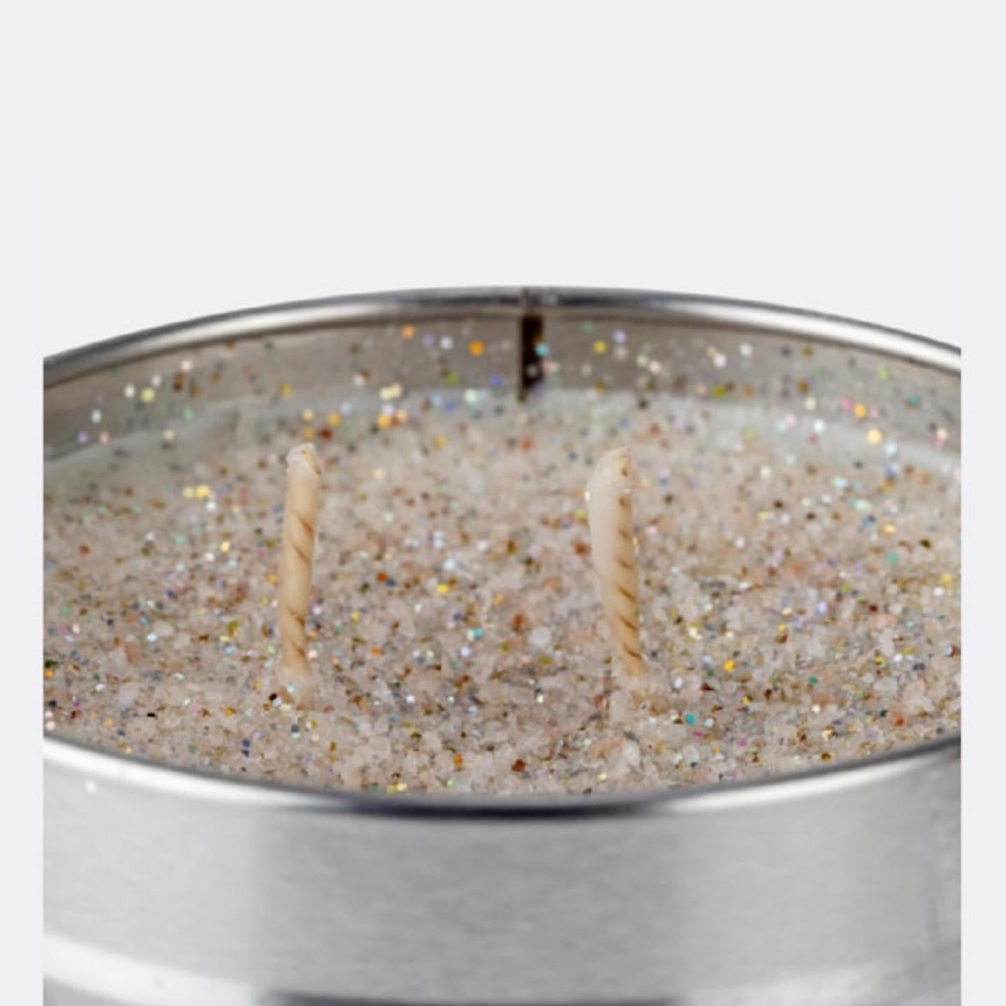 Candle in a silver tin with glittery texture on a white background