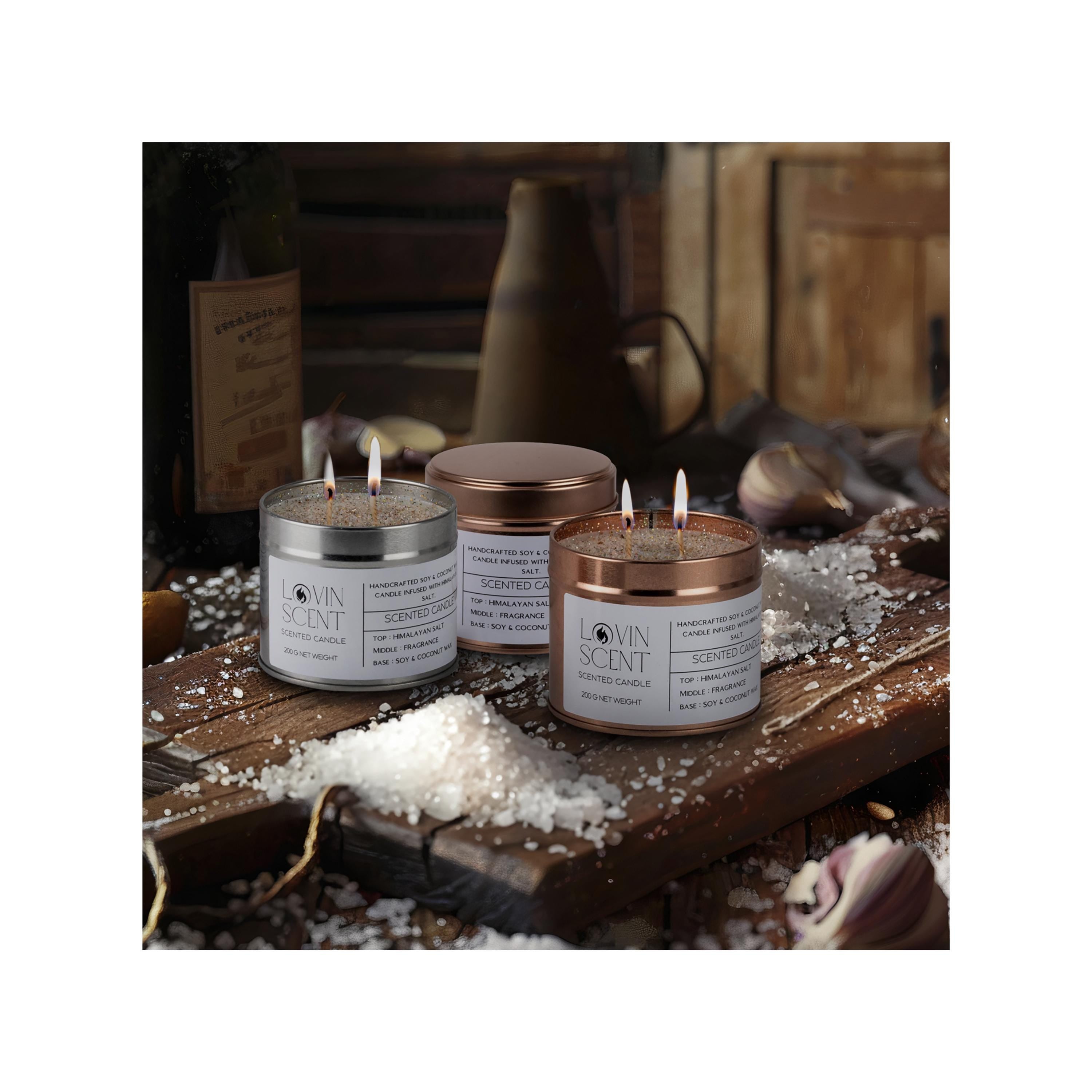 Three lit candles in metal containers on a wooden surface with salt and garlic.